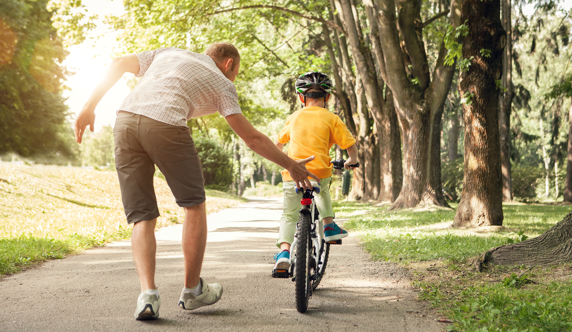 Image of man teaching a boy to ride a bike